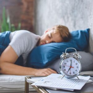 a man sleeping in bed with alarm clock